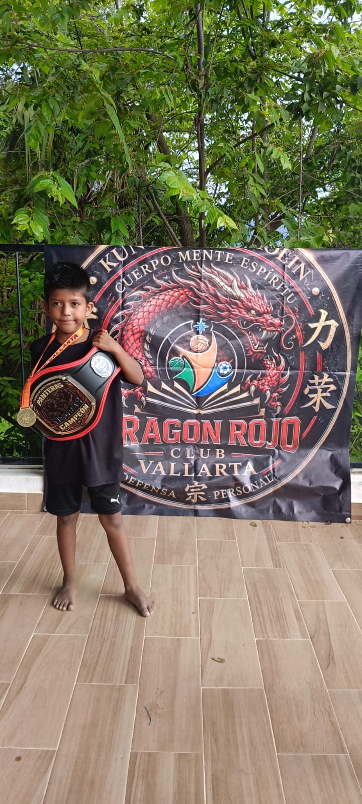 Young martial arts participant posing with a banner