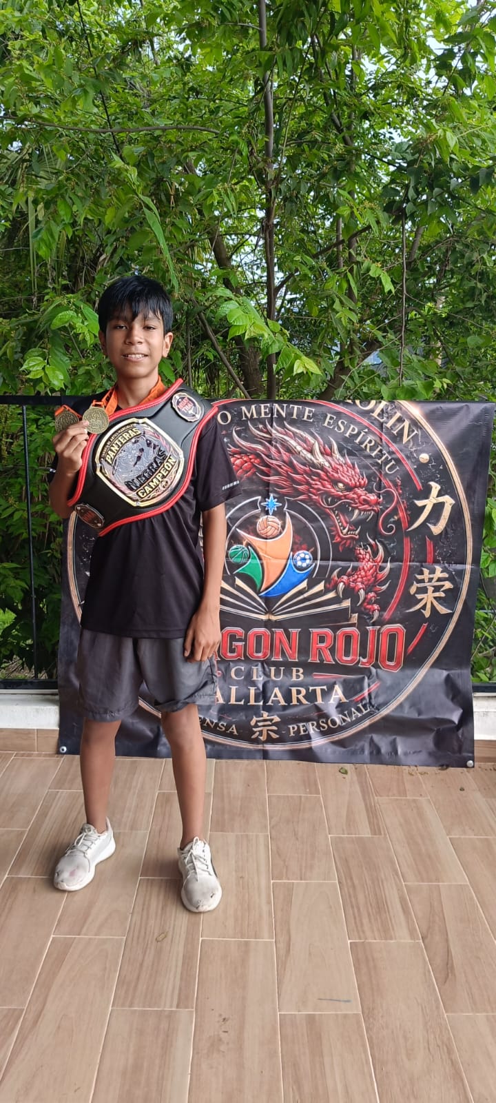 Young martial arts participant posing with a banner