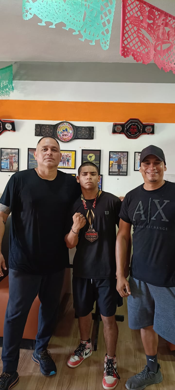 Martial arts participants posing with championship belts and medals